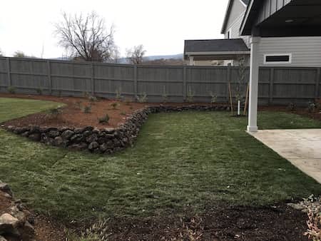 Natural rock landscaping in backyard with retaining wall