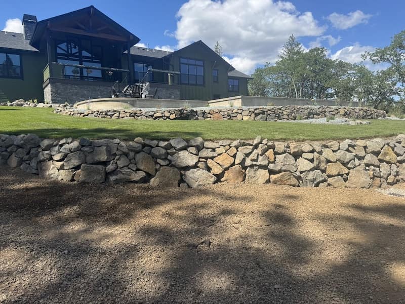 After shows multiple retaining walss of natural stone, sod and irrigation